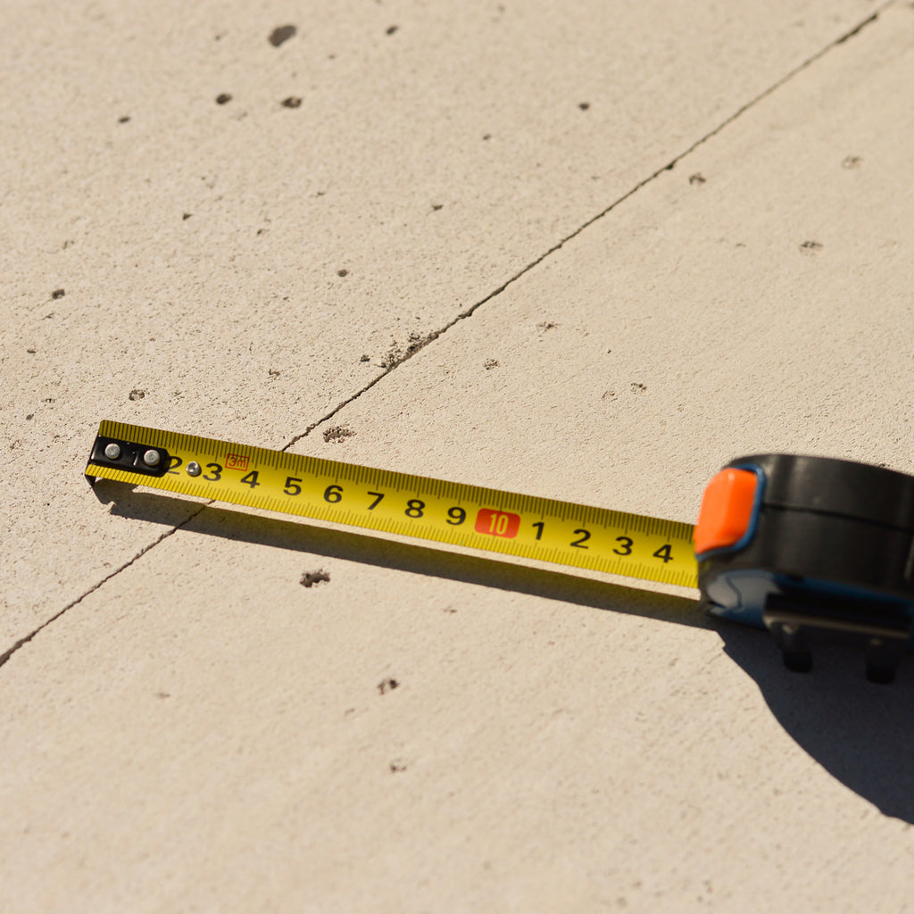 Close-up of a measuring tape on a concrete floor, illustrating precise measurements crucial for the proper installation and maintenance of strip curtains in a warehouse setting