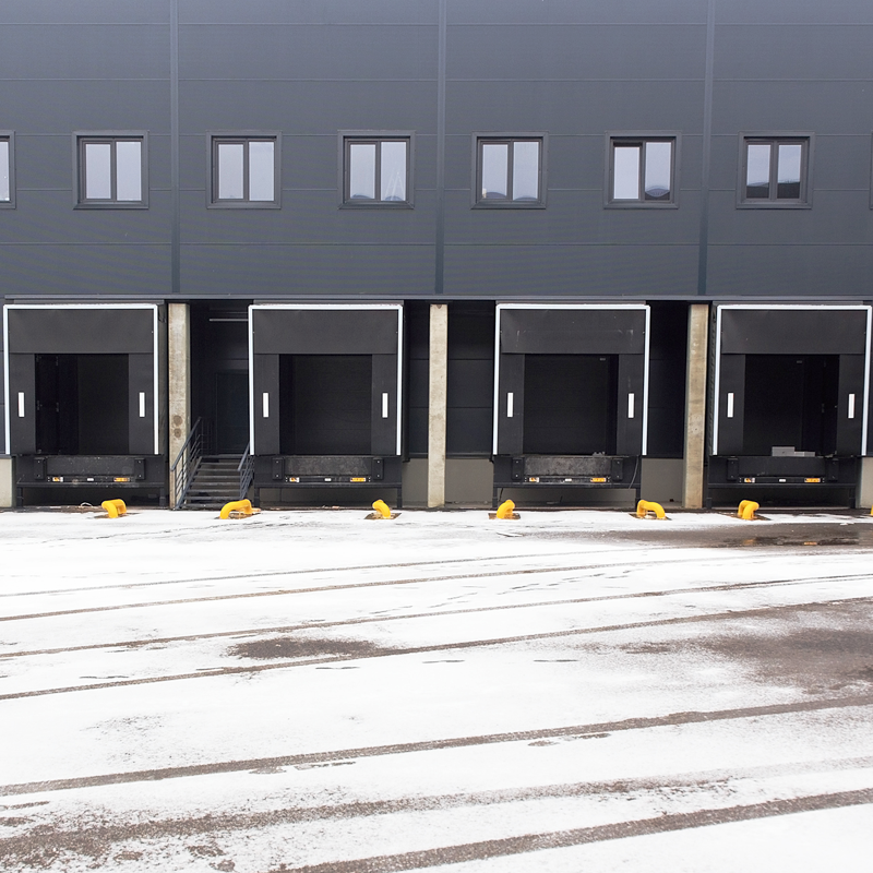 A warehouse equipped for winter with PVC strip curtains, grit bins, and safety mats at loading bays — demonstrating energy efficiency, heat retention, and safe access during cold weather.