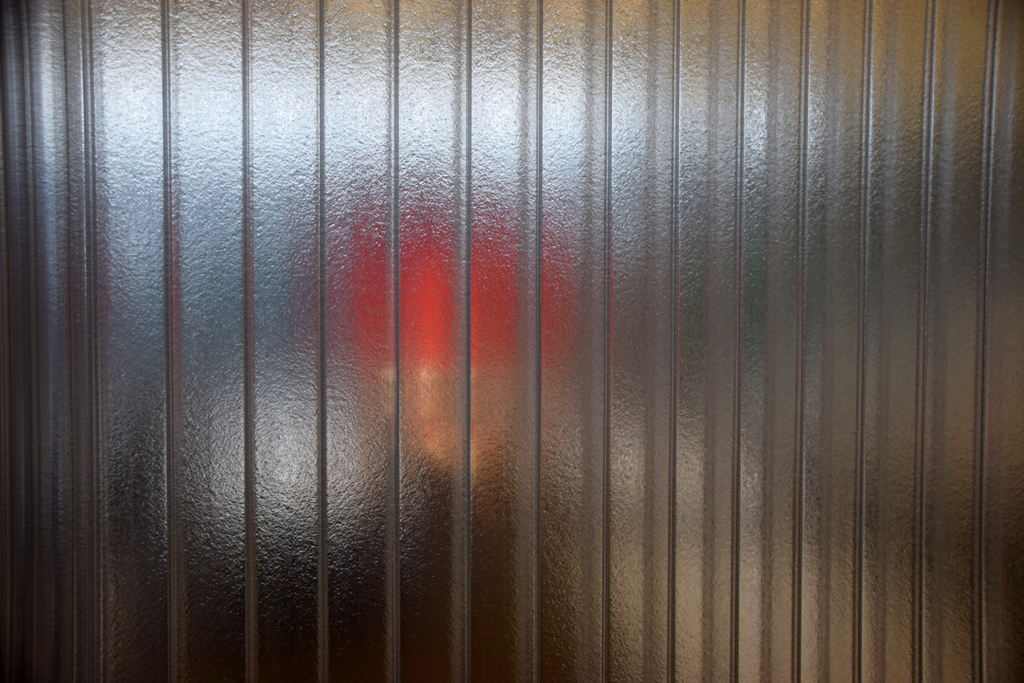 Forklift seen through clear ribbed PVC strip curtains in a warehouse doorway (strip curtain barrier for temperature and pest control).