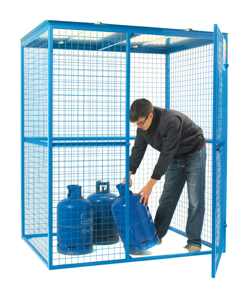 A person is placing a blue cylinder inside a blue metal security cage with a mesh design.