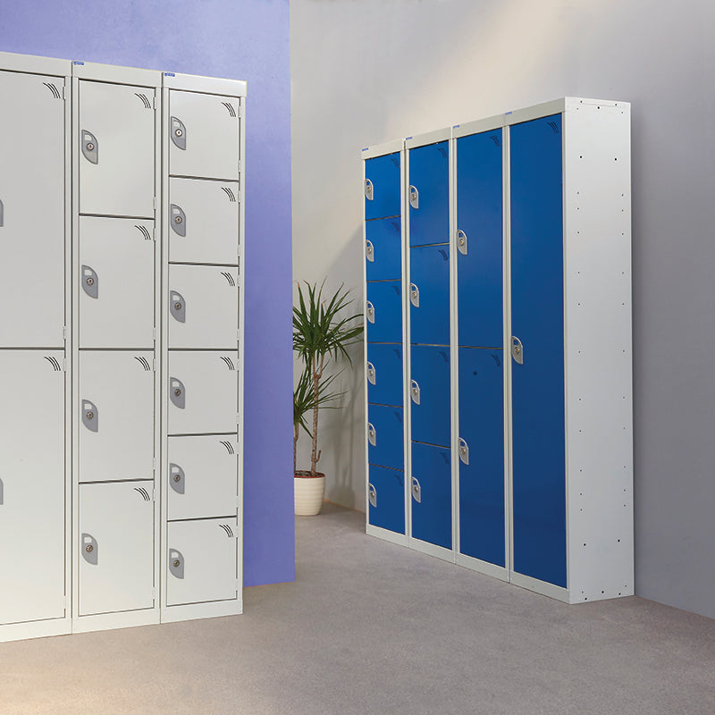 A row of white lockers with silver handles and a set of blue lockers with silver handles, both standing in a room with a plain wall and a potted plant in the background.